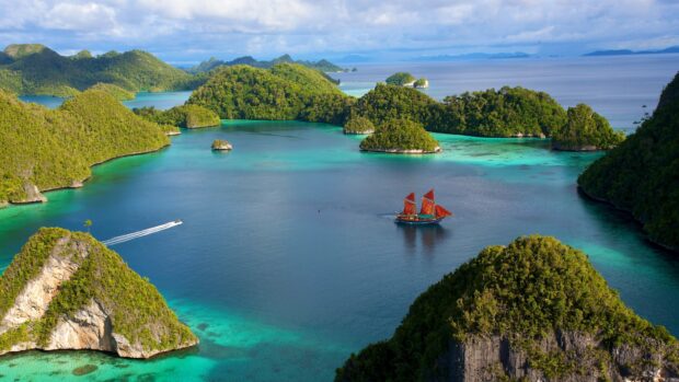 A traditional boat sailing through lush islands in the Pacific Ocean
