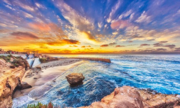 A stunning Pacific Ocean coastline with vibrant sky and rocky cliffs at sunset