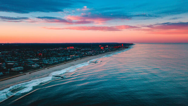 Aerial view of Pacific Ocean coastline with cityscape under colorful sunset sky