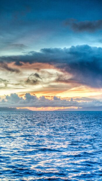 Pacific Ocean view with vibrant sky and clouds at sunset over calm water