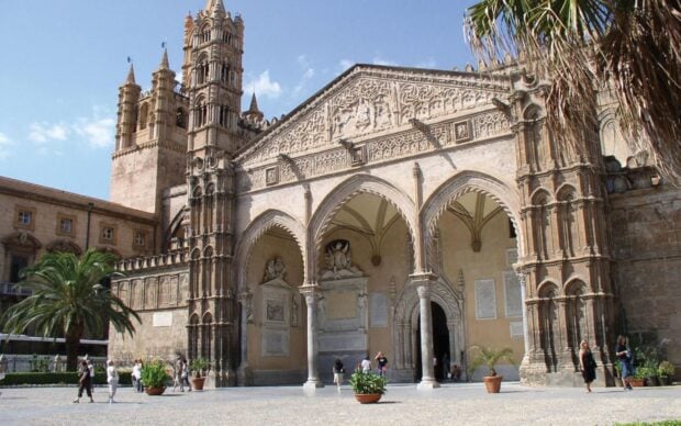 Historic Palermo architecture with detailed stone carvings and arches under clear blue sky