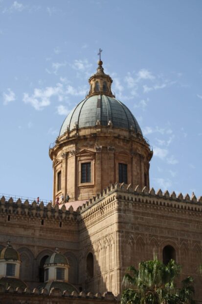 Historic Palermo architecture with a large dome and detailed stone carvings under a blue sky