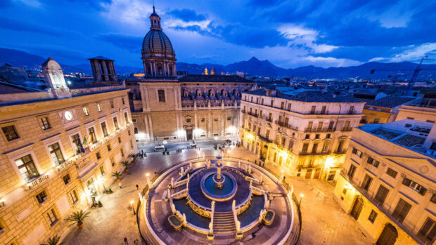 Historic Palermo city square with fountain and cathedral under blue evening sky