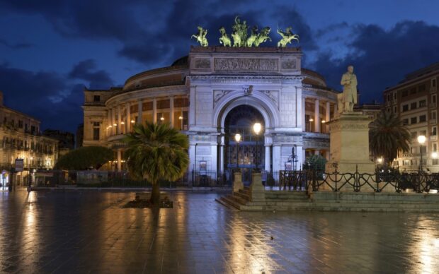 Night view of Palermo historic building with statues and palm tree
