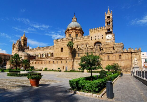 Ancient Palermo architecture with cathedral dome and clock tower under blue sky