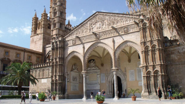 Gothic cathedral architecture in Palermo with detailed stone carvings and palm trees
