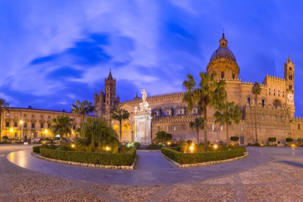 The historic Palermo architecture features a cathedral with a large dome and palm trees under a vibrant blue sky