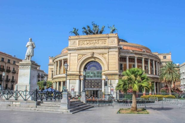 Historic building with statues and palm trees in Palermo city center