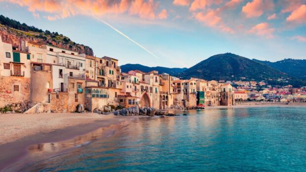 Historic buildings by the beach in Palermo with mountains in the background