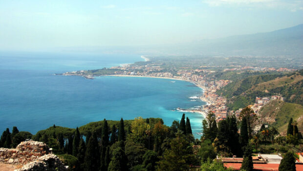 A panoramic view of Palermo coastline with turquoise sea and lush greenery in the foreground