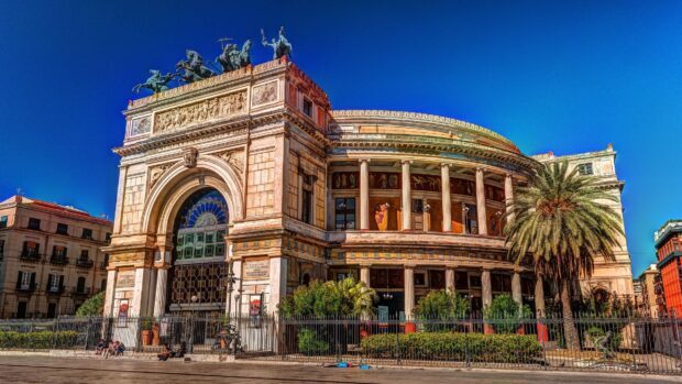 Historic Palermo architecture with ornate sculptures and palm trees under blue sky