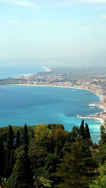 Coastal Palermo cityscape with blue sea and lush green trees in clear sunlight