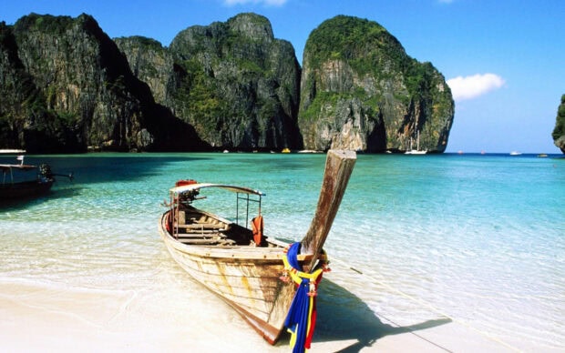 Traditional longtail boat near limestone cliffs in Phi Phi crystal clear water