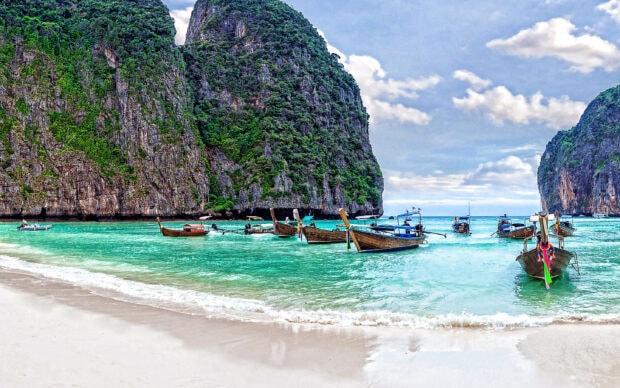 Traditional longtail boats near green cliffs in Phi Phi islands