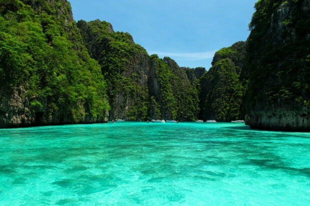 Clear turquoise waters surround lush green cliffs at Phi Phi