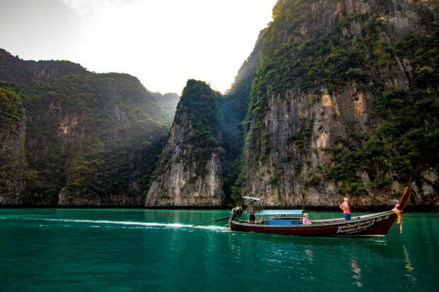 Traditional boat sailing near limestone cliffs in Phi Phi islands