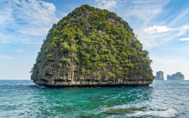 A large lush green island in Phi Phi surrounded by clear turquoise ocean water