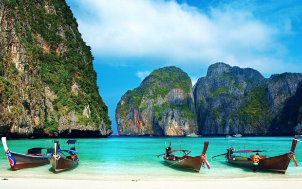 Traditional wooden boats on turquoise water at Phi Phi islands cliffs