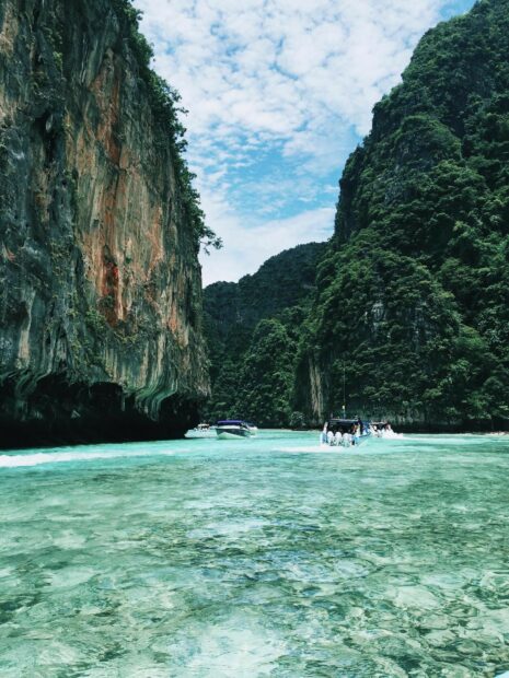Clear turquoise water with boats passing through limestone cliffs at Phi Phi