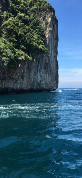 Cliff with lush greenery at Phi Phi Island and deep blue sea under clear sky