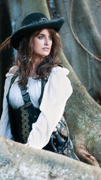 A pirate woman in detailed costume standing by a tree in Pirates Of The Caribbean scene