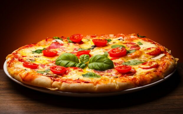 A delicious pizza topped with fresh tomatoes and basil leaves on a wooden table