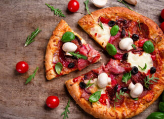 A delicious pizza with mushrooms and fresh basil on a wooden surface