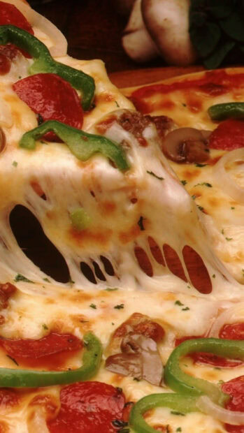 A close up of a pizza slice with melted cheese green peppers and pepperoni on top