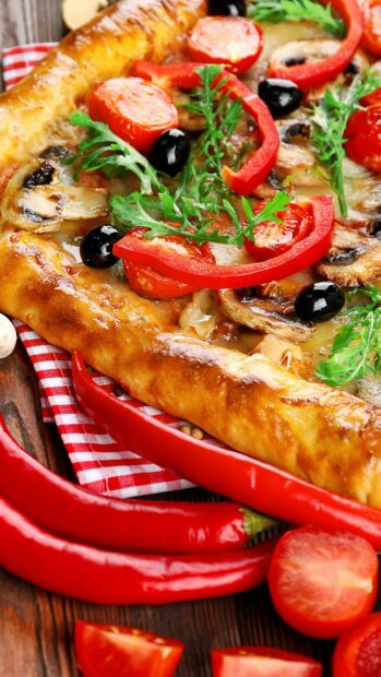 A delicious pizza topped with fresh tomato slices red bell peppers black olives mushrooms and arugula on a crispy crust