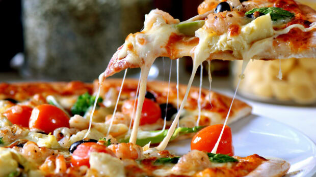 A delicious pizza slice with melted cheese and fresh toppings including tomatoes and spinach