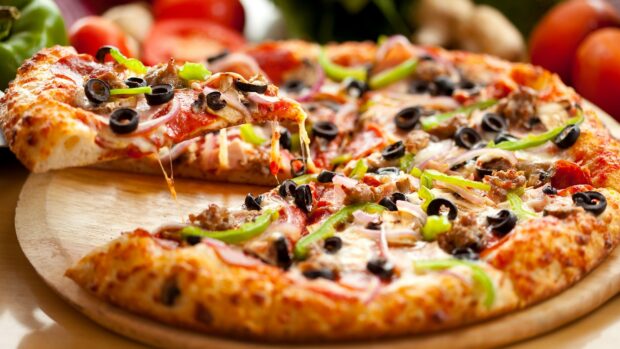 A delicious pizza with olives green peppers and onions on a wooden board