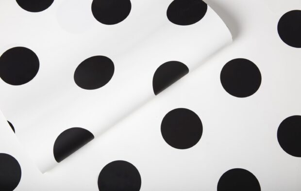 Black polka dot pattern on white surface with a folded edge in a polka dot design