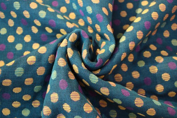 Close up of fabric with colorful polka dot pattern on teal textile surface