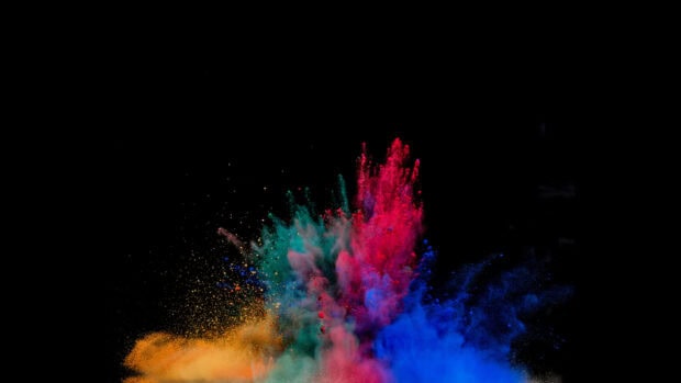 Vibrant powder explosion with red blue green and orange colors on black background