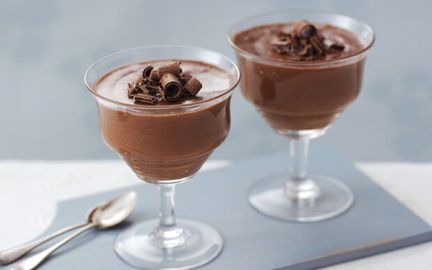 Two chocolate pudding desserts garnished with chocolate shavings in elegant glass cups