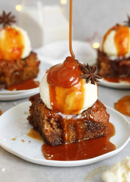 Caramel sauce drizzling on pudding topped with star anise on a dessert plate
