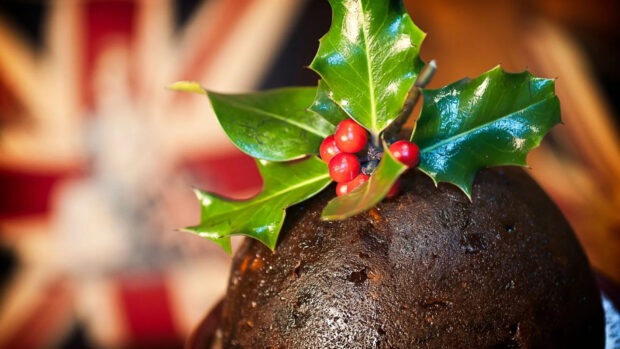 A close up of pudding topped with holly leaves and red berries