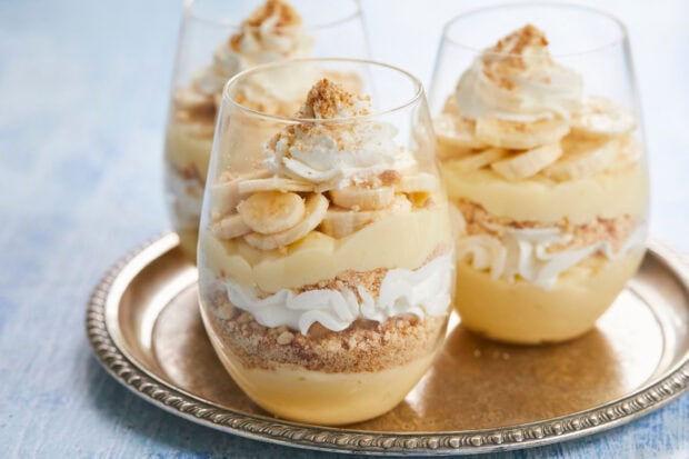 Creamy pudding dessert layered with banana and whipped cream in clear glass cups