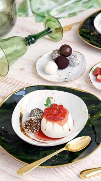 A creamy pudding topped with red berries served with assorted dessert balls on elegant plates