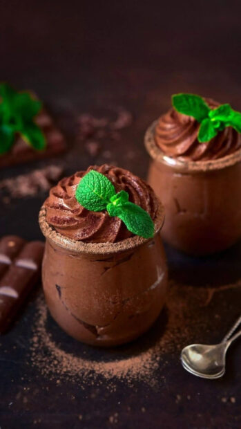 Rich chocolate pudding topped with fresh mint leaves in glass jars