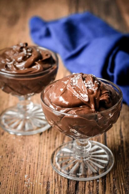 Smooth chocolate pudding served in glass dishes on wooden table