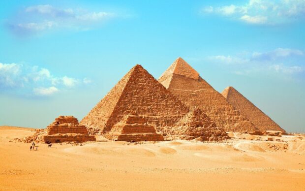 The pyramids of Giza standing tall under a clear blue sky in the desert landscape