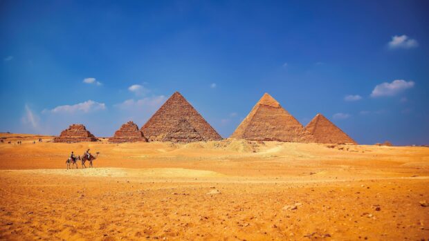 The ancient pyramids of Giza stand tall under a clear blue sky in the desert