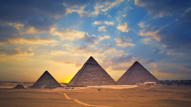 The ancient Pyramids of Giza under a colorful sky at sunset in the desert