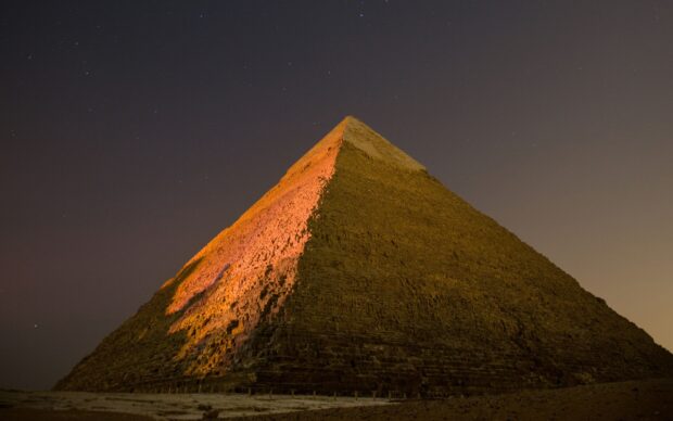 Ancient pyramids of Giza illuminated under a starry night sky