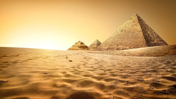 The ancient Pyramids of Giza surrounded by golden desert sand under a bright sky