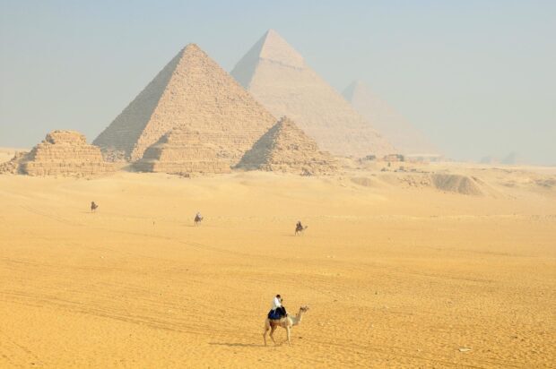 A man riding a camel near the pyramids of Giza desert landscape