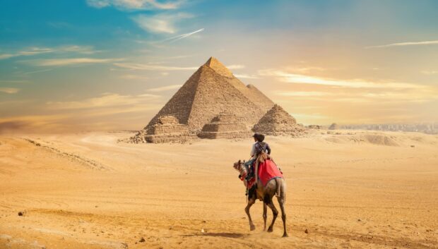 A traveler riding a camel near the pyramids of Giza desert landscape