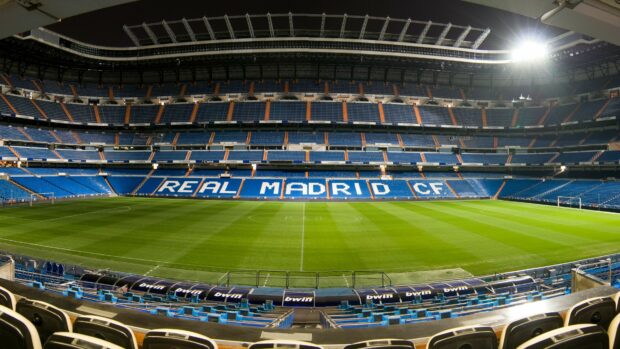 A panoramic view of Real Madrid Cf stadium with empty seats and green field at sunset