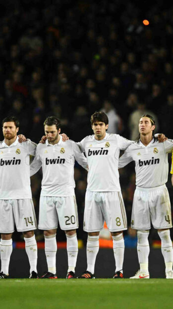Real Madrid Cf players standing in a line on the field in their white kits